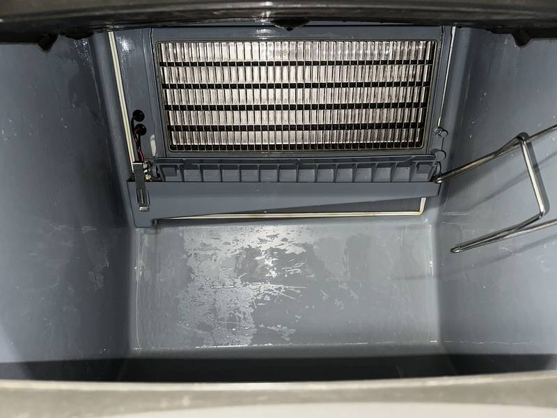 Inside a unit cabinet: a finned coil above a gray pan
